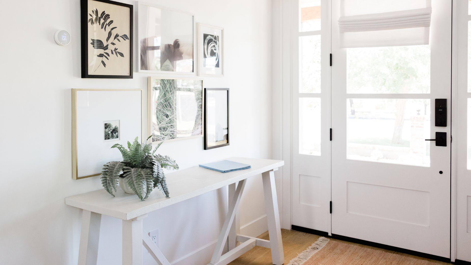 Minimalist entryway with white console table, fern, and gallery wall