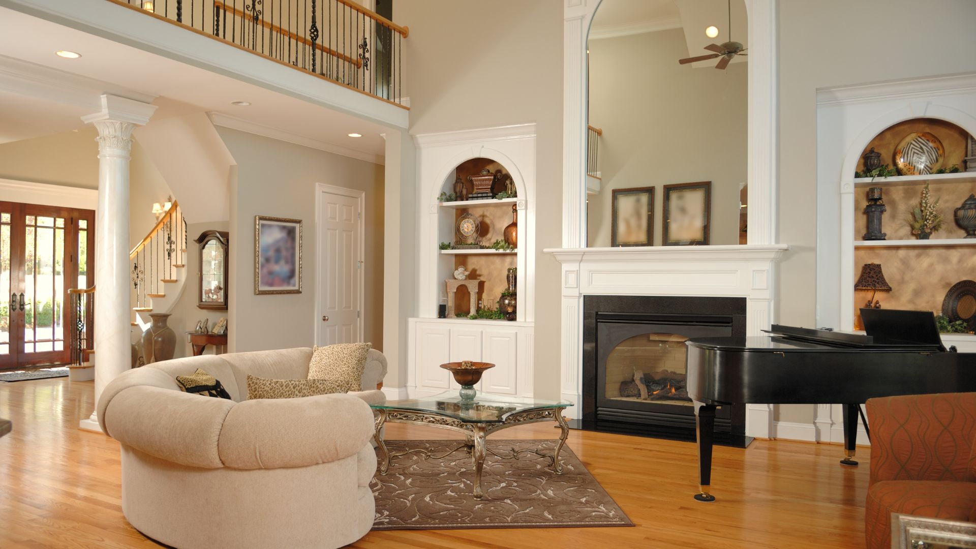 Elegant living room with fireplace, piano, arched built-ins, and curved sofa