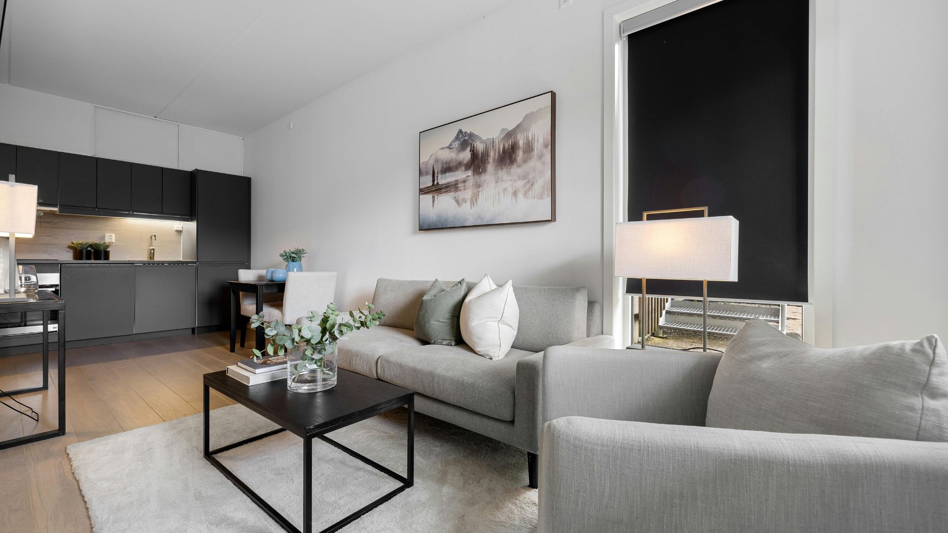 Modern minimalist living room with gray sofa and mountain landscape artwork