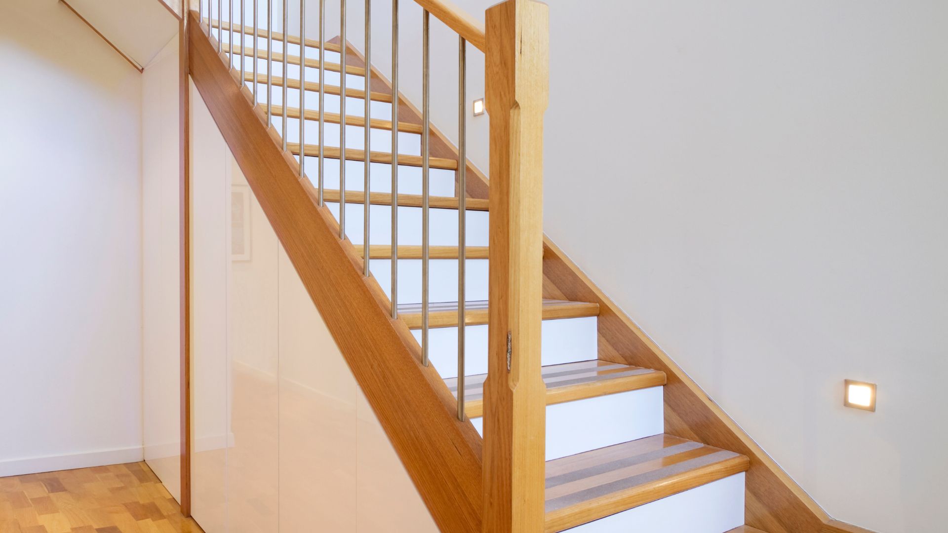 Wooden staircase with metal railings in a minimalist white interior