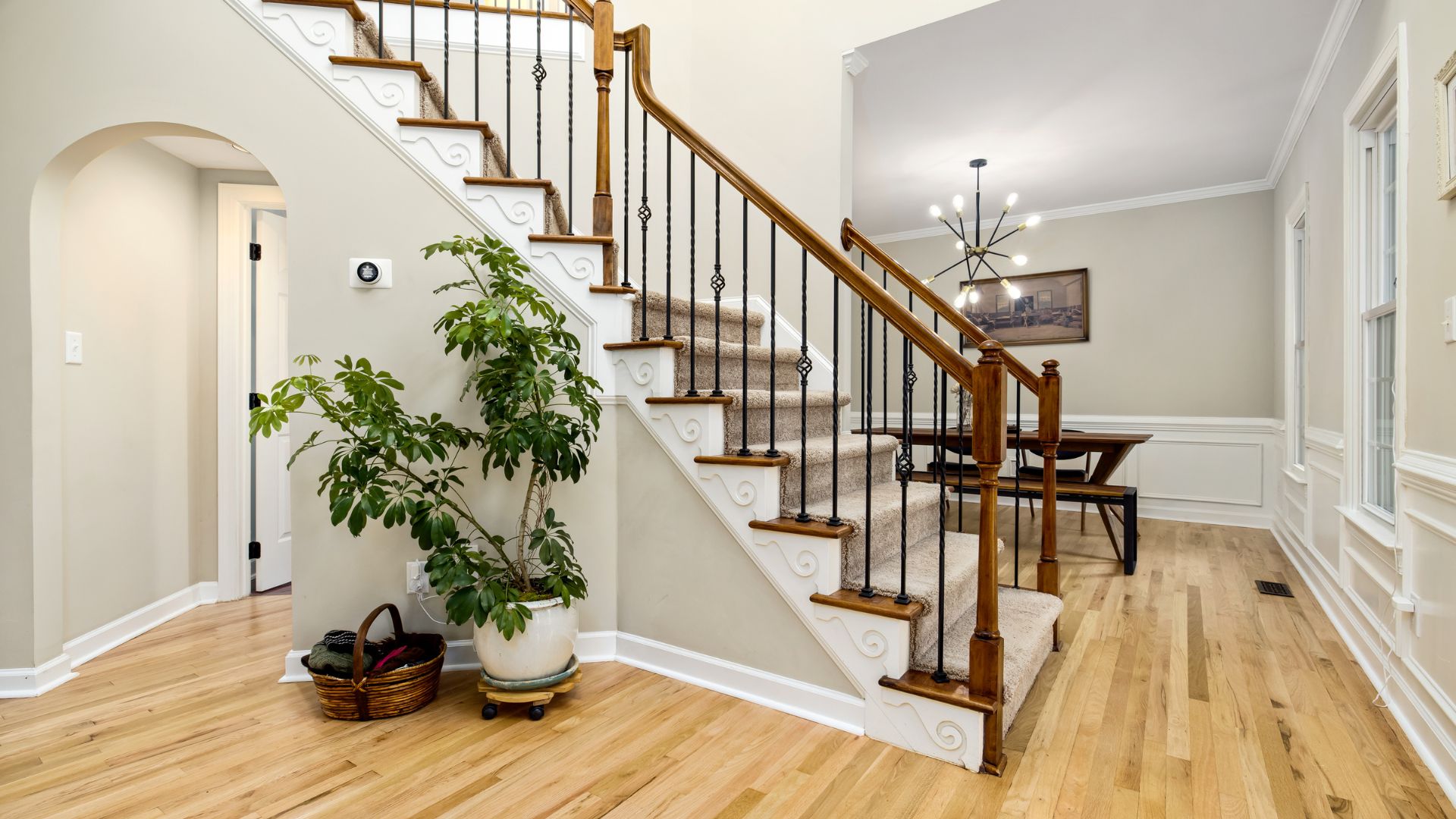 Elegant interior with wooden staircase, carpet runner, and potted plant