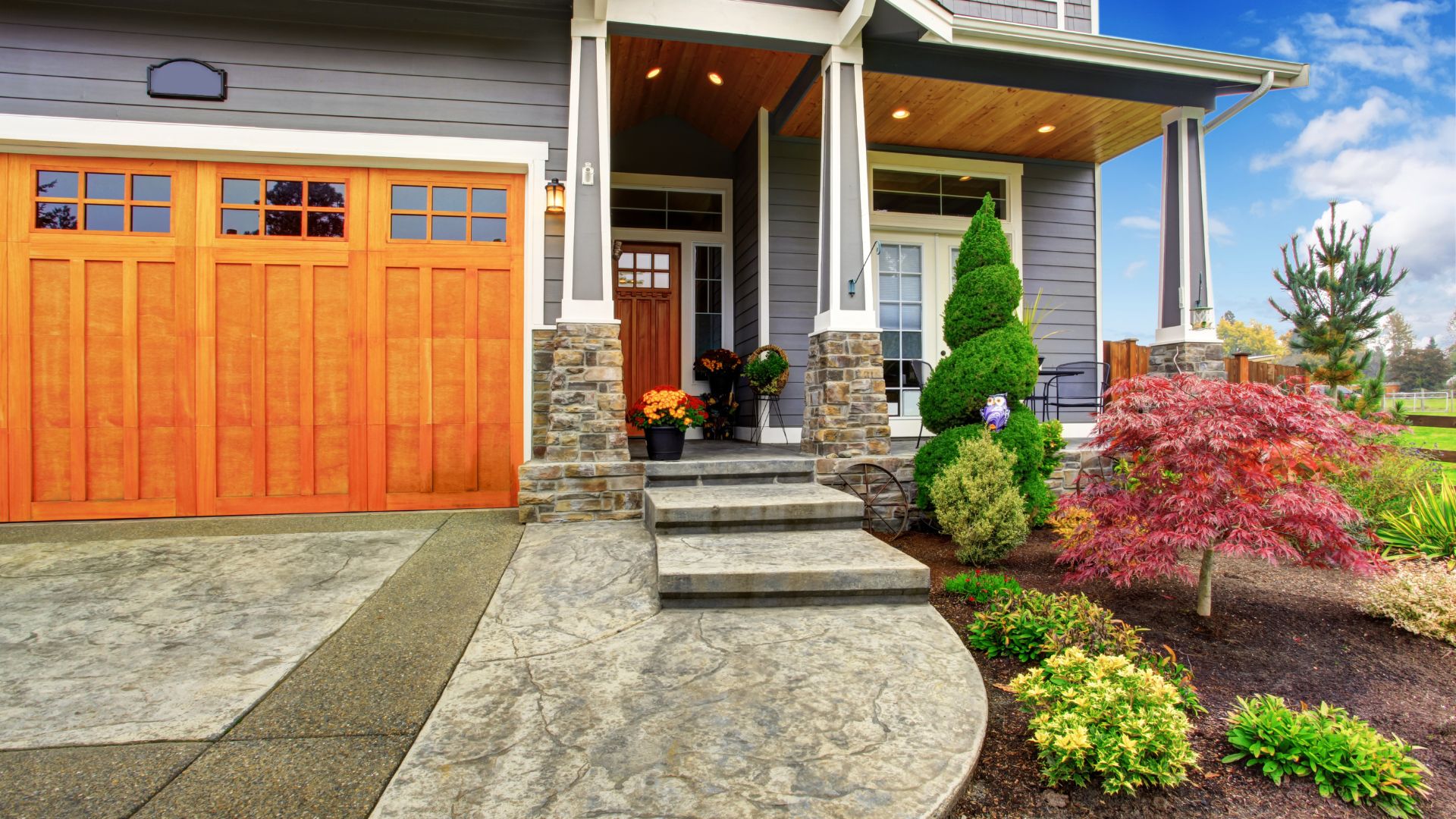 Modern craftsman house with orange garage door and well-manicured landscaping