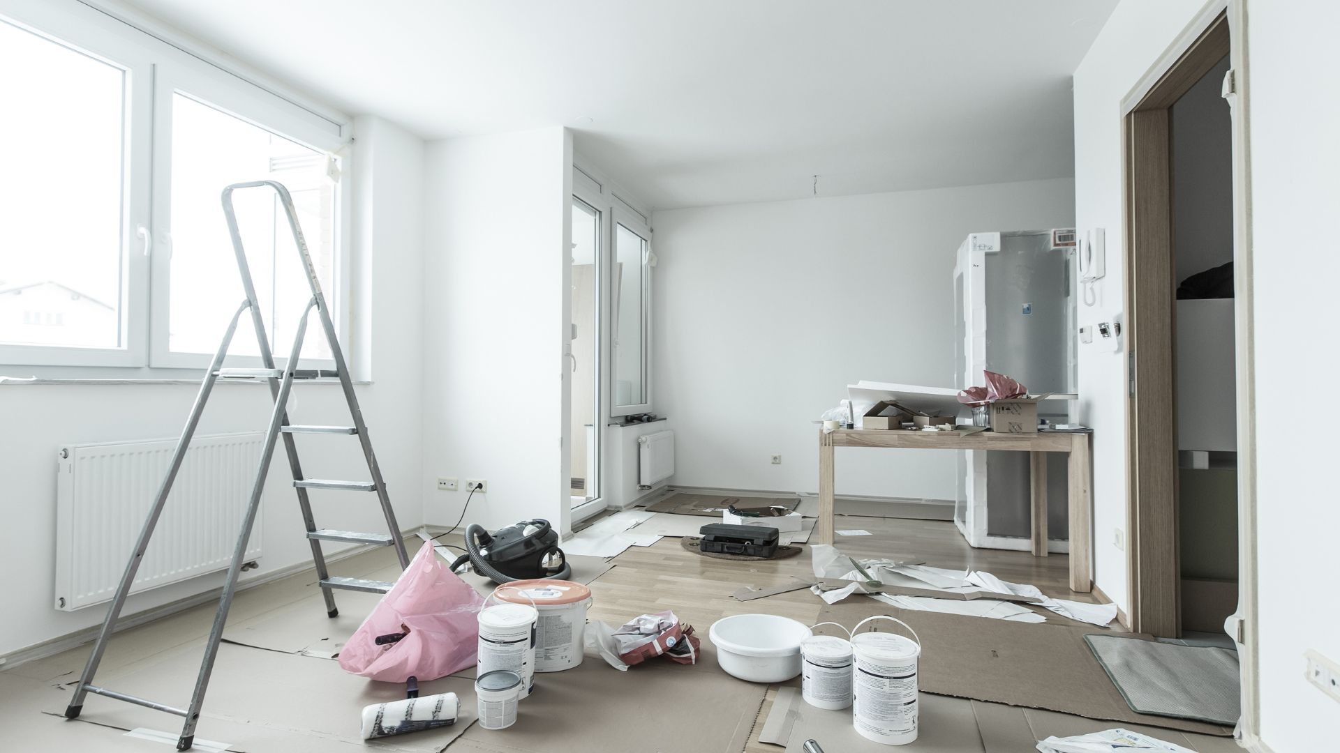 Home renovation in progress with painting supplies, ladder, and scattered materials