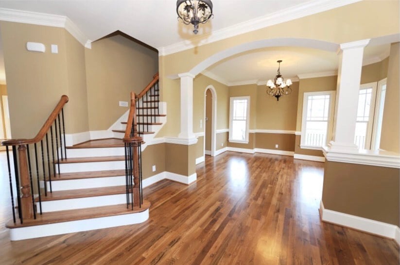 Empty interior with wooden staircase, hardwood floors, and warm neutral walls