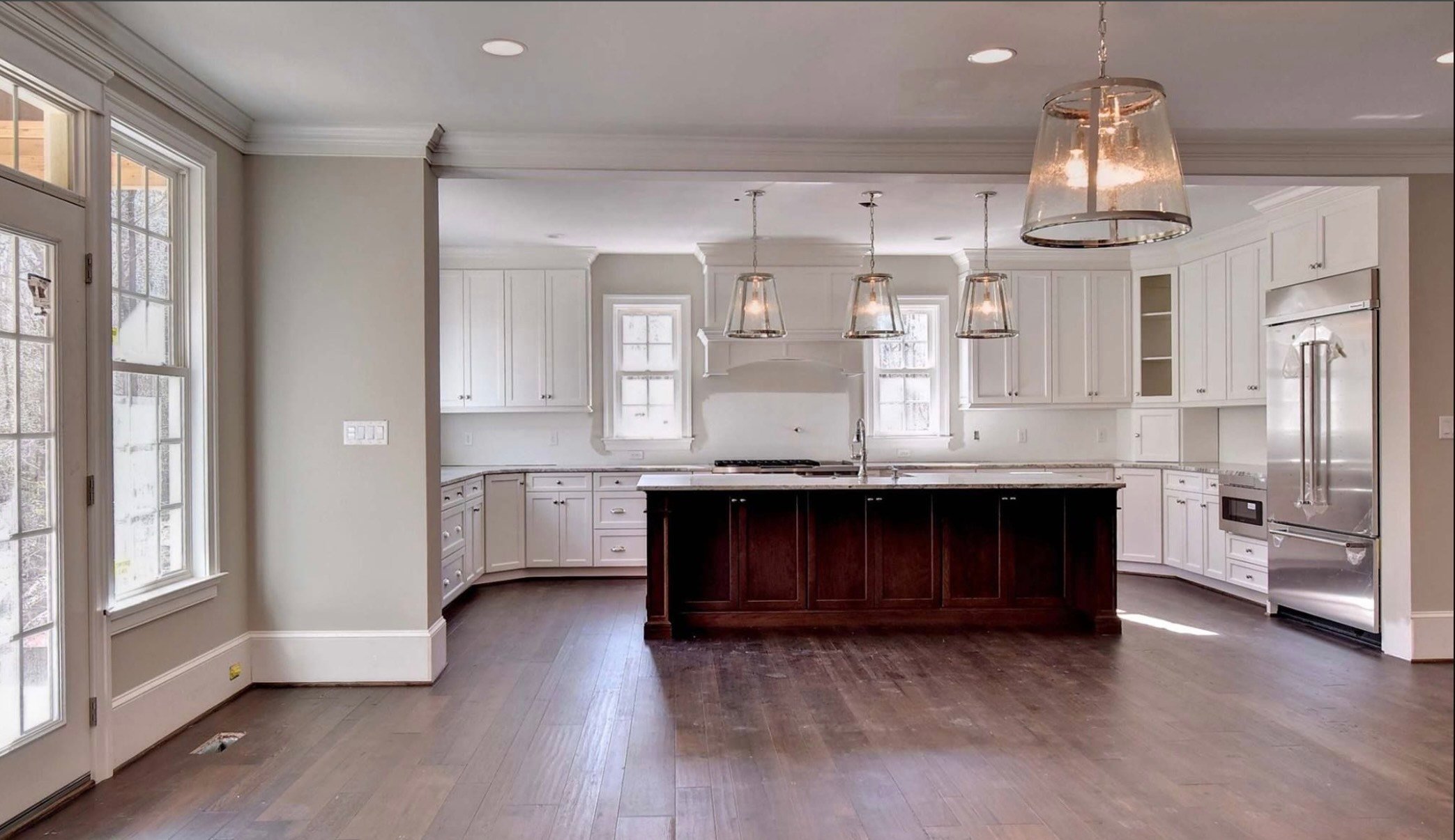 Modern kitchen with white cabinets, dark island, and glass pendant lights