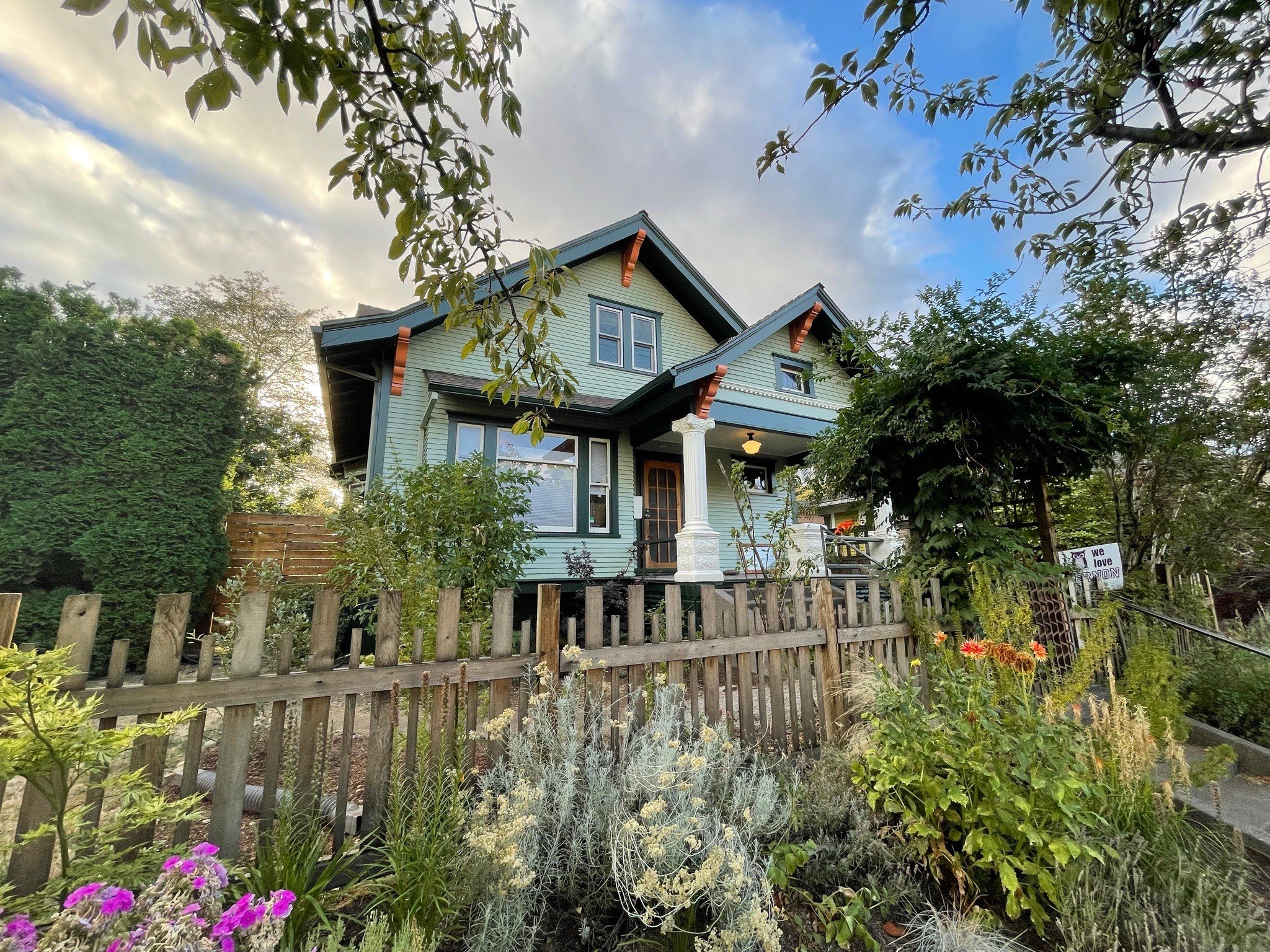 Charming blue craftsman house with white picket fence and lush garden