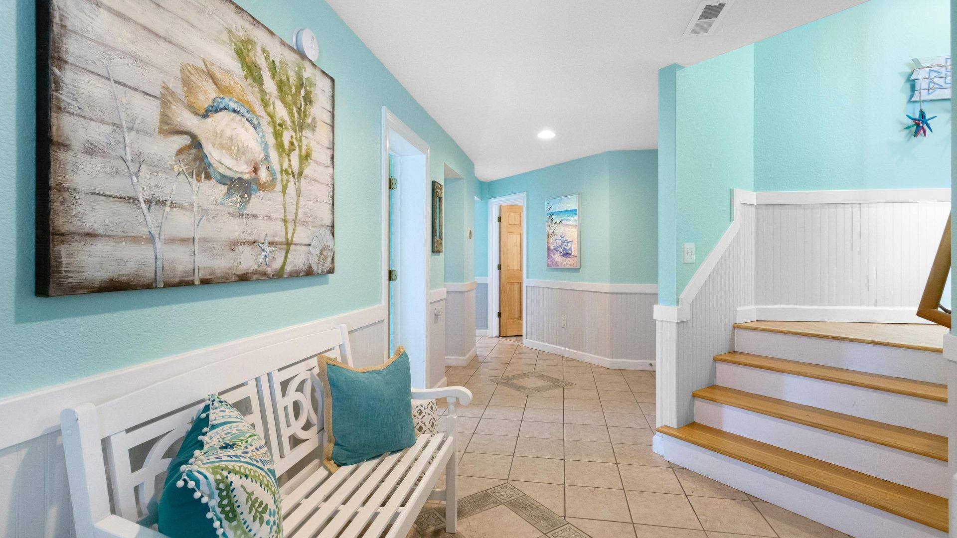 Coastal-themed entryway with blue walls, white bench, and bird artwork